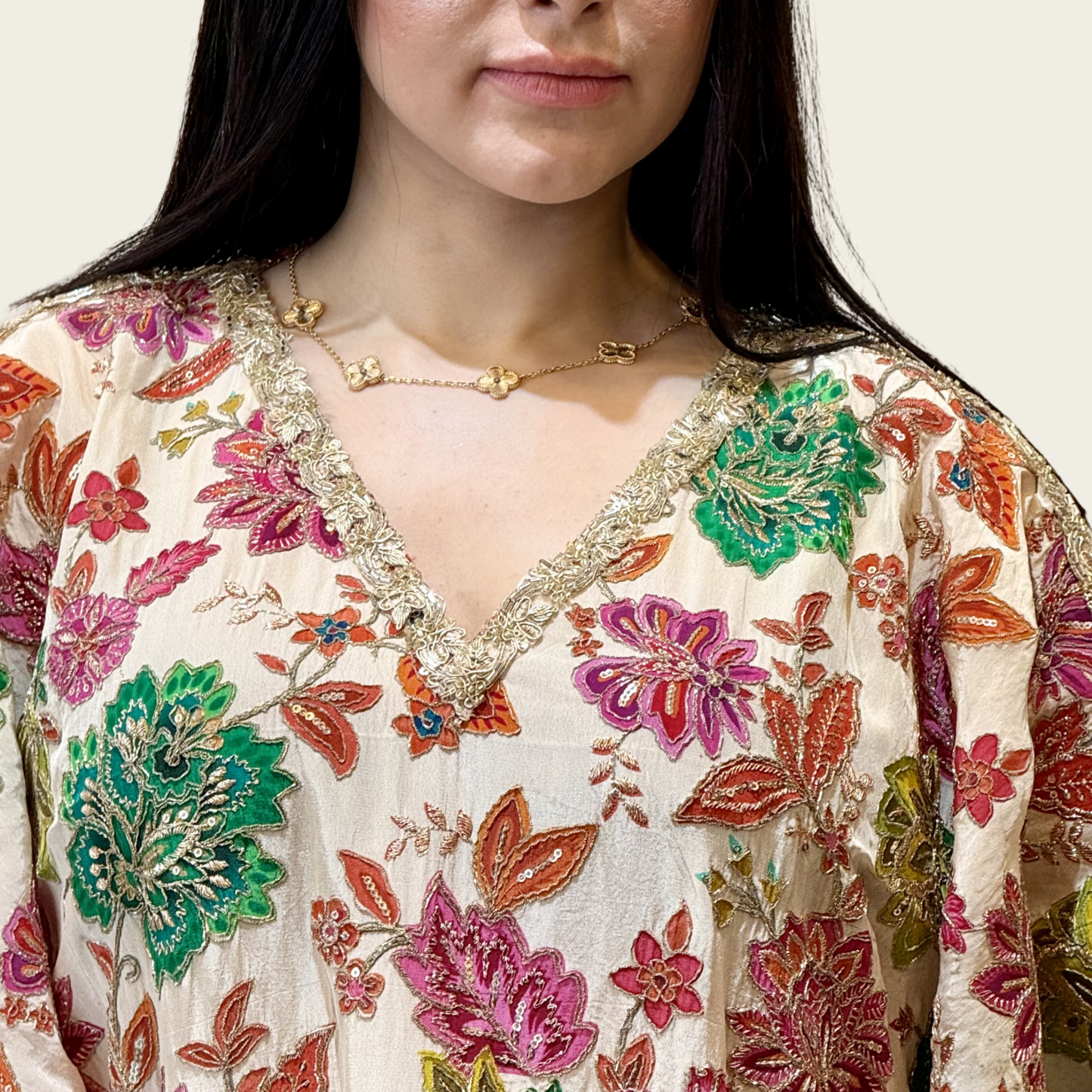 Close-up of the emerald green, magenta pink, and orange floral embroidery on Rubeena Ameen crepe fabric