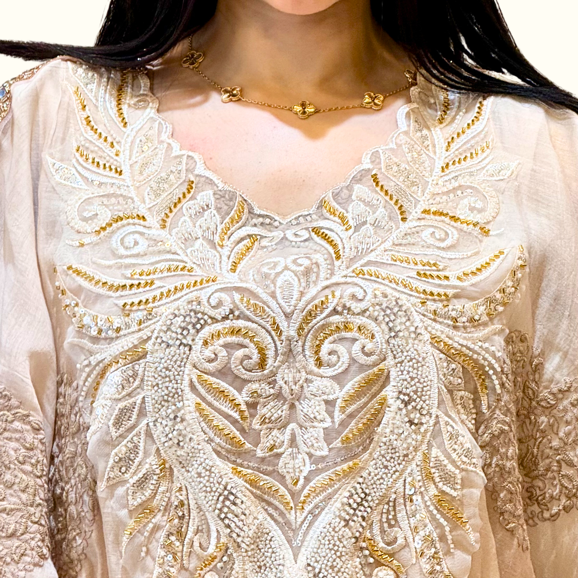 Close-up of the intricate heavy embroidery detailing on the neck and sleeves of Rubeena Ameen ivory dress