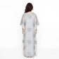 A woman viewed from the back wearing a long sheer kaftan dress in pale blush pink with silver heart-shaped sequin embroidery, set against a plain white studio background.
