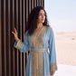 Close-up of the gold and crystal embroidery on the neckline, sleeve cuff and belt of a sky blue handmade Moroccan kaftan.