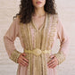 Close-up of a soft blush pink kaftan with a gold filigree belt and delicate gold scroll trim detailing.