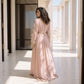 Back view of a woman wearing a floor-length blush pink handmade Moroccan kaftan with gold scroll trim.