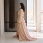 Side profile of a woman wearing a blush pink floor-length kaftan with gold trim detailing, showing the flowing silhouette.