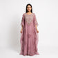 A woman modeling a dusty pink kaftan dress with intricate silver and gold embroidery on the bodice and scattered floral patterns on the flowing skirt, set against a plain white studio background.
