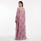 A woman modeling a long, sheer mauve-pink kaftan dress with floral embroidery and sequin embellishments, shown from the back against a plain white studio background.