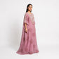 A woman modeling a long, flowing dusty pink kaftan dress with intricate floral embroidery and sheer sleeves, photographed against a plain white studio background.