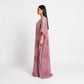 A woman modeling a long, flowing mauve-pink kaftan dress with intricate floral embroidery, shown in profile against a plain white studio background.