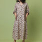 A woman modeling a long-sleeved, knee-length floral dress with a V-neck and side pockets, standing against a solid sage green studio background.