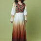 A woman modeling a long maxi dress with a geometric patterned bodice and an ombré skirt fading from cream to rust and dark brown, set against a solid olive green studio background.