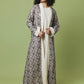 A woman modeling a long, open-front abaya with a detailed black and gray geometric pattern over a cream inner dress, set against a solid sage green studio background.