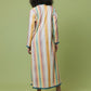 A woman viewed from behind wearing a long-sleeved maxi dress with vertical pastel stripes in yellow, orange, pink, blue, and white, paired with black heels, set against a solid light green studio background.