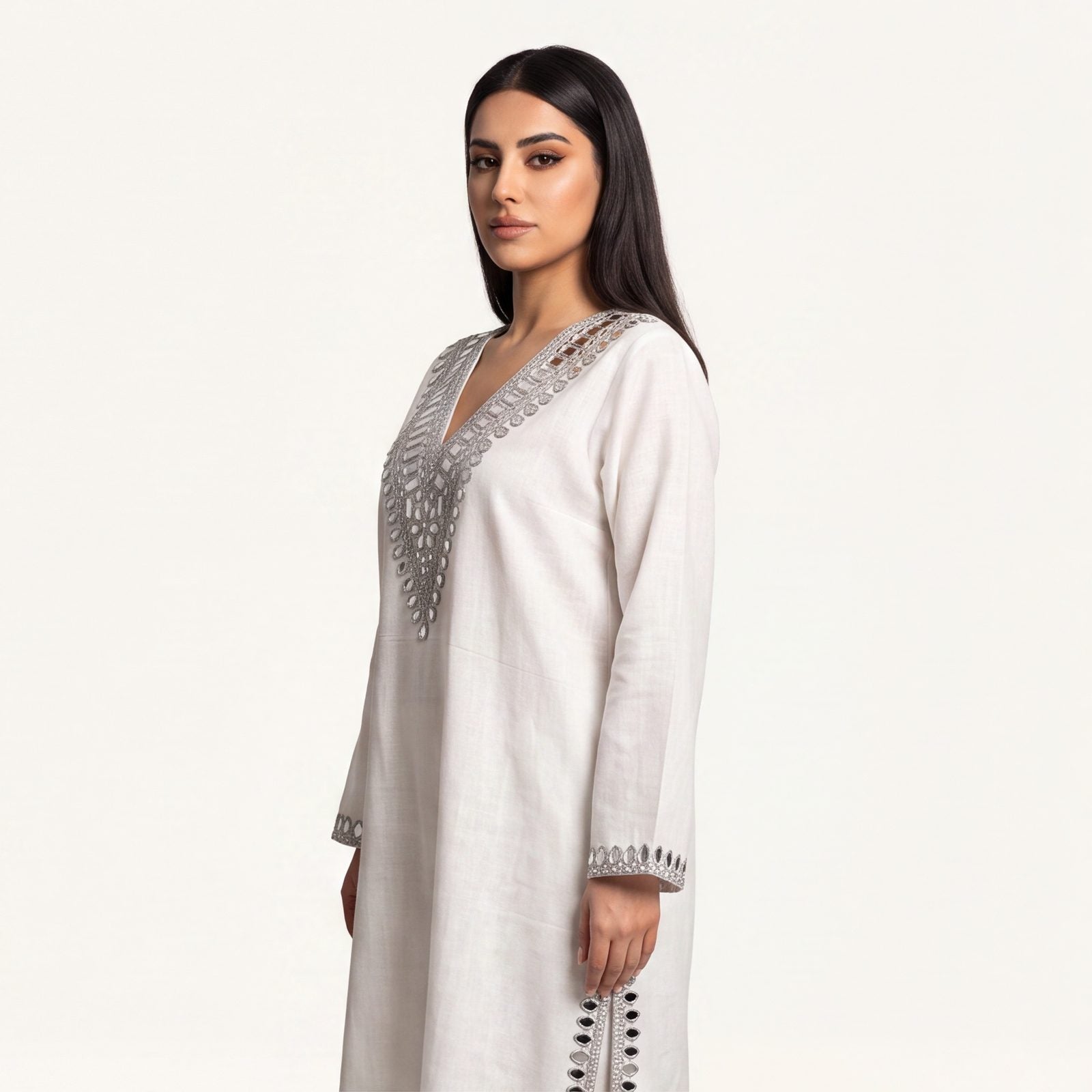 Close-up of silver mirror-embroidered V-neckline on ivory pure linen kaftan
Description: Close-up front view of the hand-finished silver mirror-work embroidery on the V-neckline of the ivory pure linen kaftan