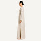 Side profile of beige pure linen kaftan showing flowing silhouette and mirror-trimmed side slit