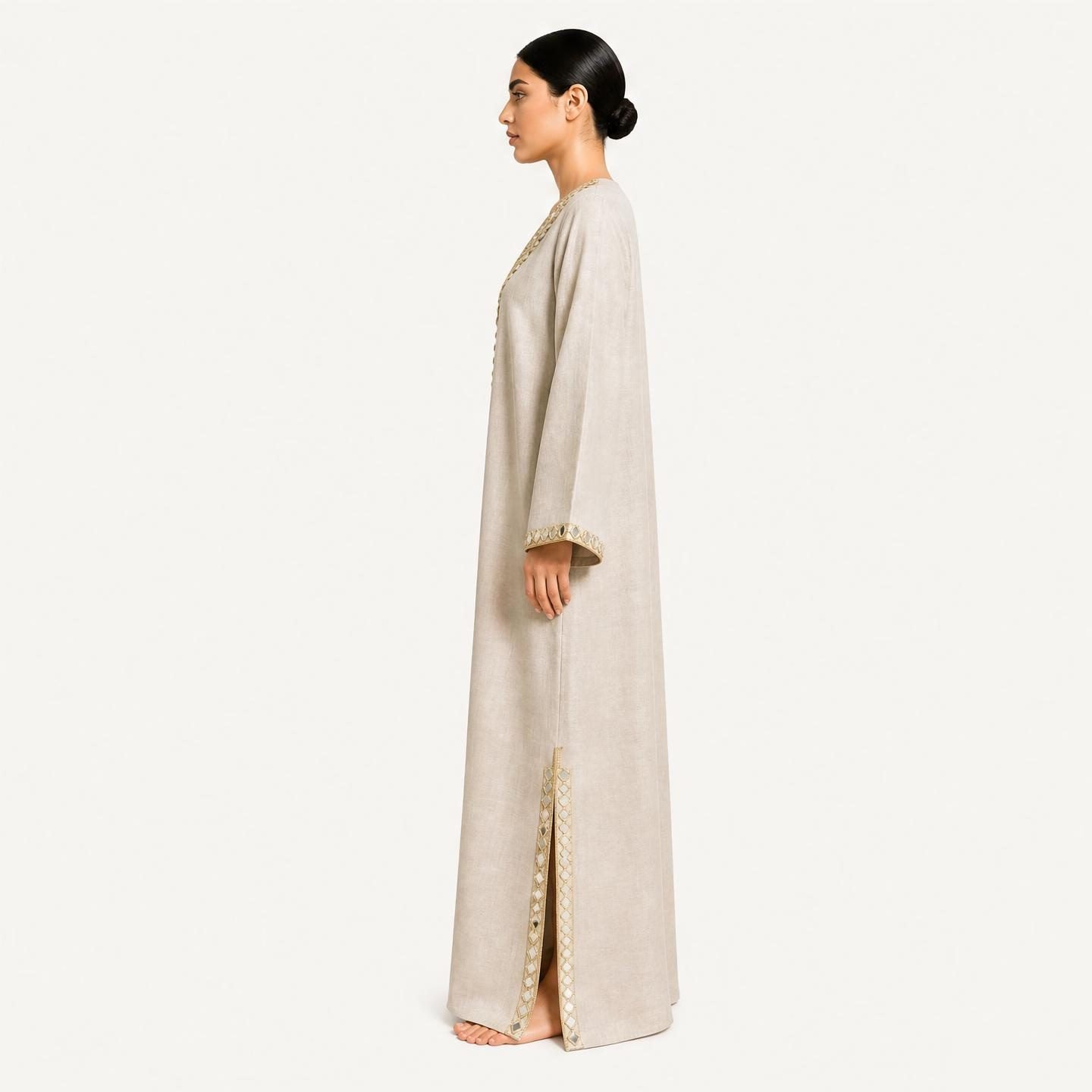 Side profile of beige pure linen kaftan showing flowing silhouette and mirror-trimmed side slit
