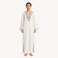 Woman wearing an ivory pure linen kaftan with silver mirror-embroidered V-neckline, front view
Description: Front view of the RUBEENA AMEEN pure linen kaftan in ivory white, featuring silver mirror-work embroidery at the neckline and side slits, with a relaxed floor-length silhouette.