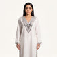 A woman modeling a long-sleeved white kurta with silver mirror work embroidery around the V-neck and cuffs, set against a plain off-white background.