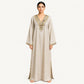 Woman wearing a beige pure linen kaftan with gold mirror-embroidered V-neckline, front view