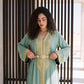 Close-up of a sage green kaftan with a gold filigree belt and fine embroidered trim.